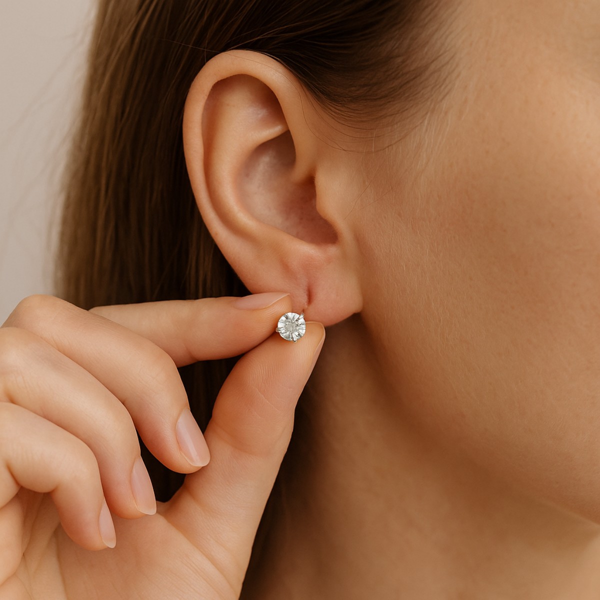 Gros plan sur une jeune femme en train d’ajuster une boucle d’oreille dorée devant un miroir. Cette image illustre le soin apporté au perçage d’oreille et la routine quotidienne pour éviter qu’un trou ne se rebouche.
